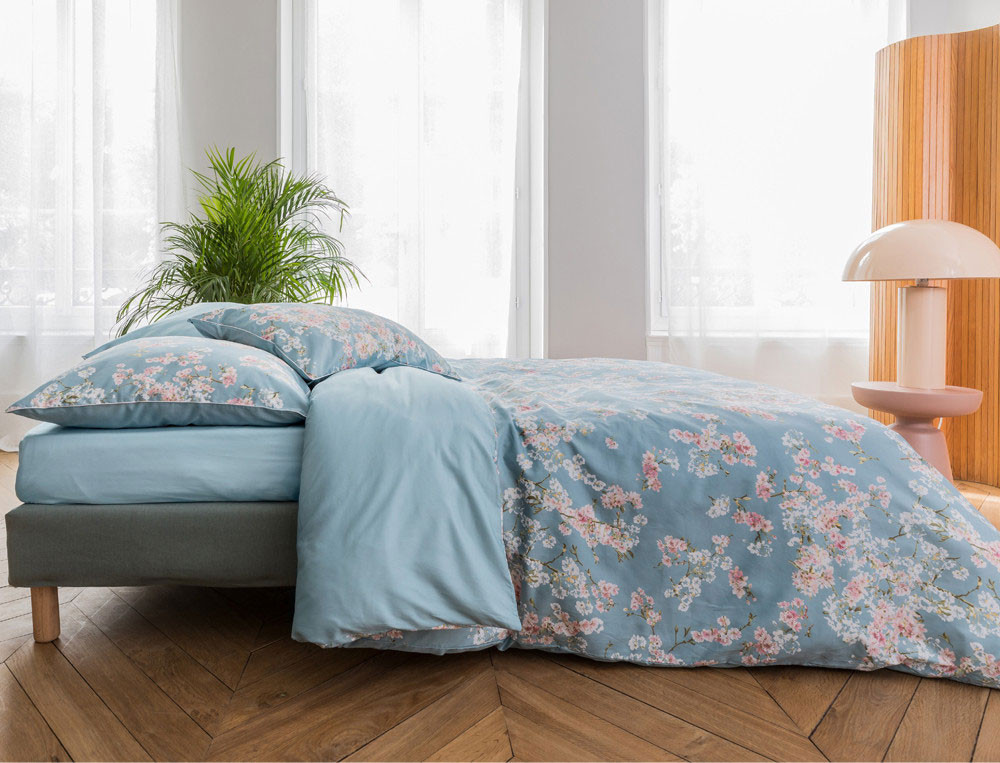 Linge de lit imprimé fleuri avec touches de blanc mat. Uni bleu ciel. Satin 100% coton, 118 fils/cm2. Florescence